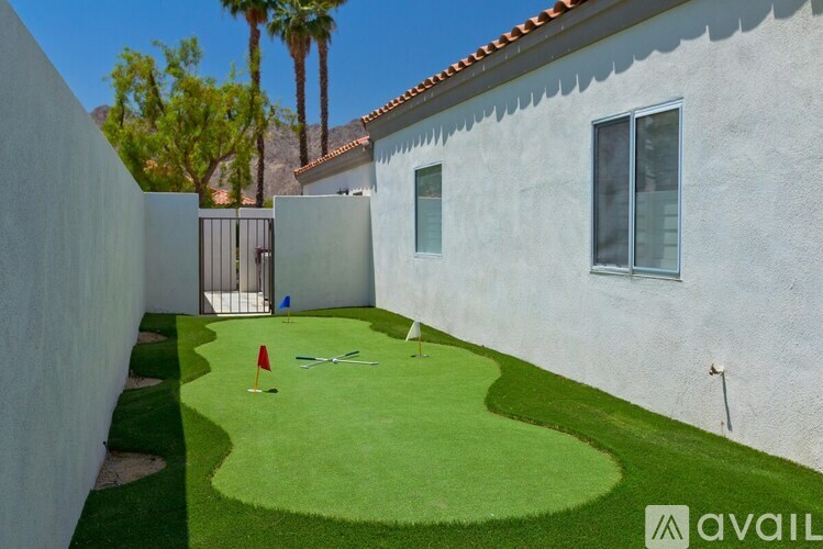 A small backyard with a green lawn and a white house.