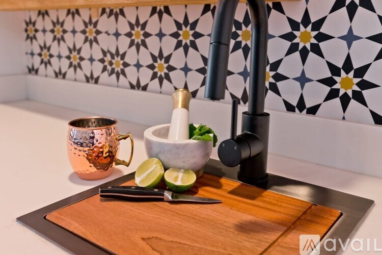 A kitchen counter with a sink, a bowl of lime, and a mug.
