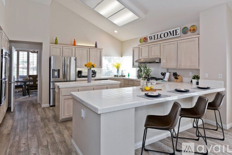 A kitchen with a white island and brown chairs.