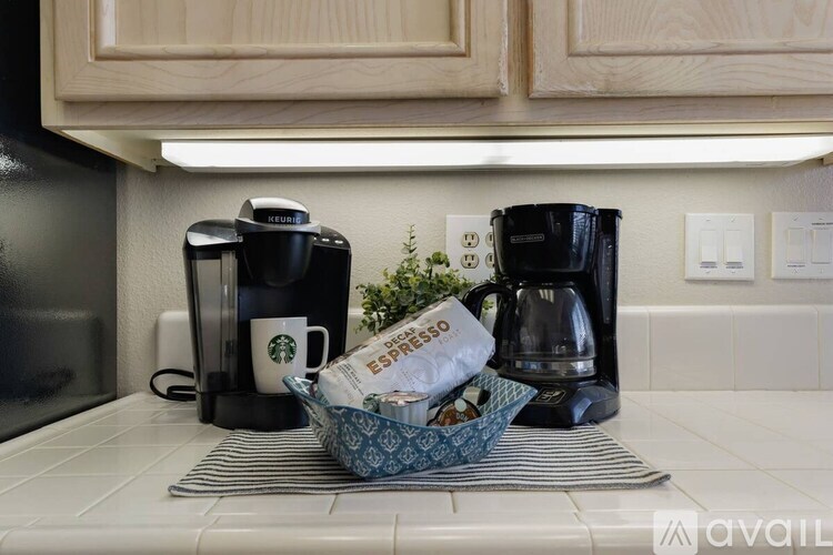 A kitchen counter with a basket of groceries and two coffee makers.