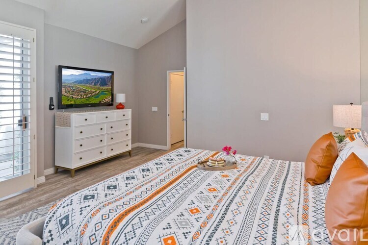 A bedroom with a large bed and a television on a cabinet.
