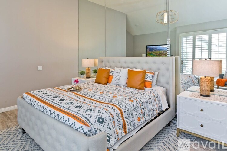 A bedroom with a large bed and a nightstand with a lamp.