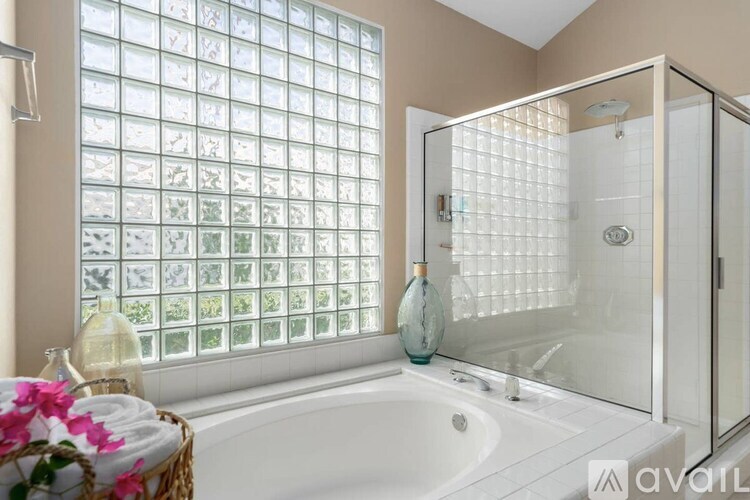 A bathroom with a large tub, a glass shower, and a window with a grid of glass panes.