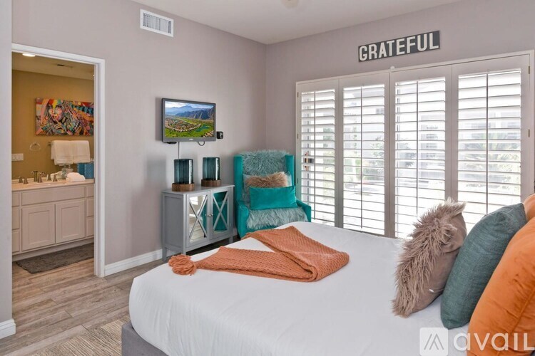 A bedroom with a bed, a dresser, and a TV mounted on the wall.