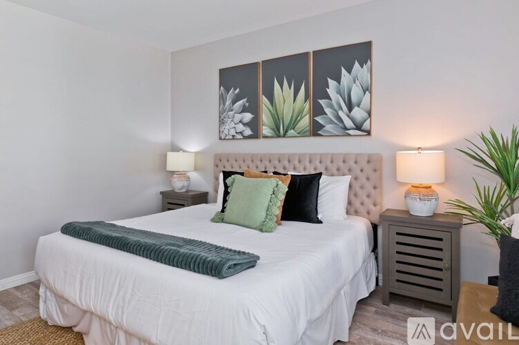 A bedroom with a large bed and a headboard with a picture of a plant on it.