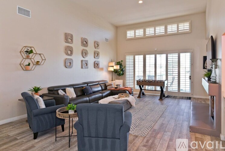 A living room with a grey sofa, a black leather couch, a wooden coffee table, and a TV on the wall.