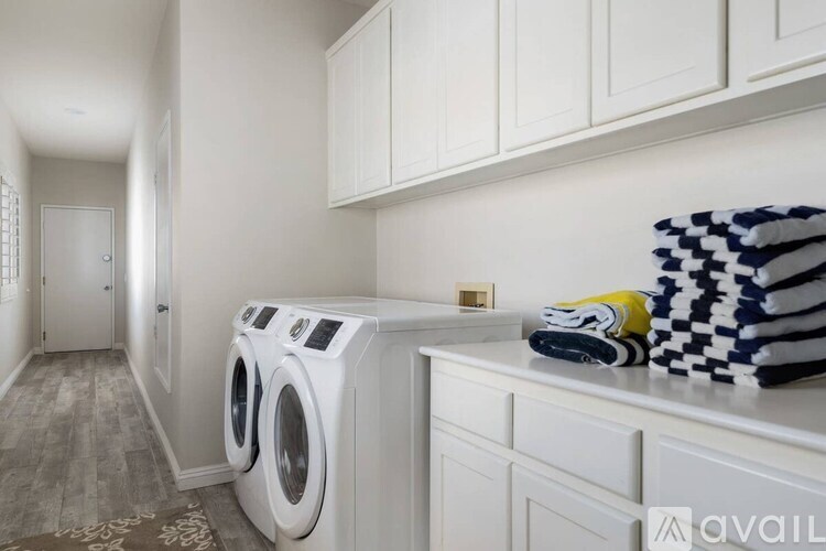 A laundry room with a washer and dryer, a white cabinet, and a checkered blanket.