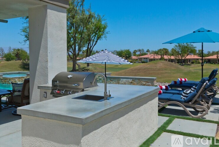 A modern outdoor kitchen with a built-in grill and a blue umbrella.