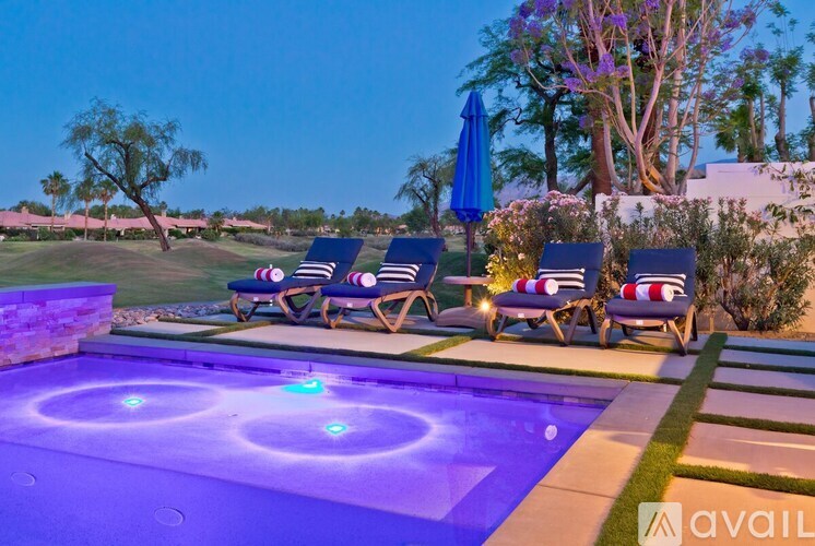 A pool with a hot tub and lounge chairs.
