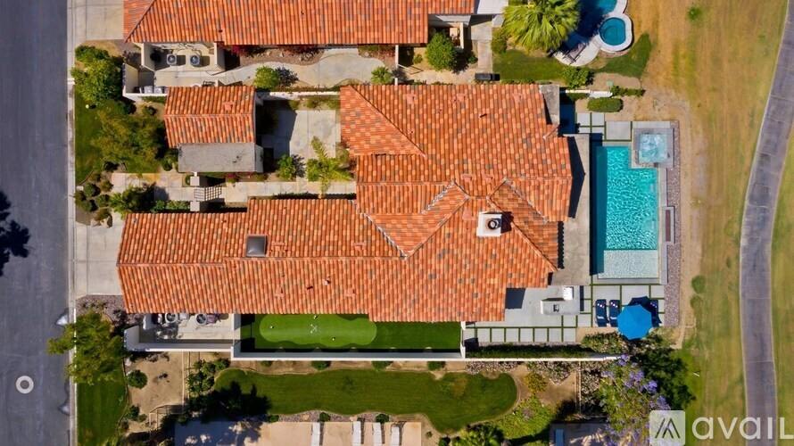 A large house with a red tiled roof and a swimming pool in the backyard.