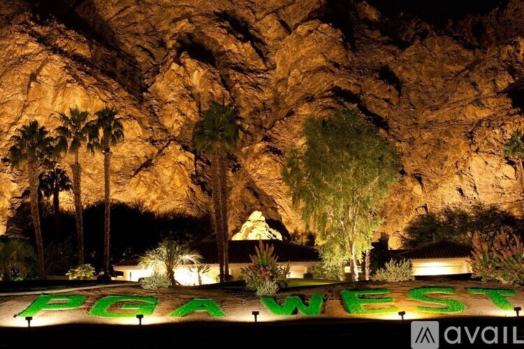 A sign that says PGA West is lit up at night.