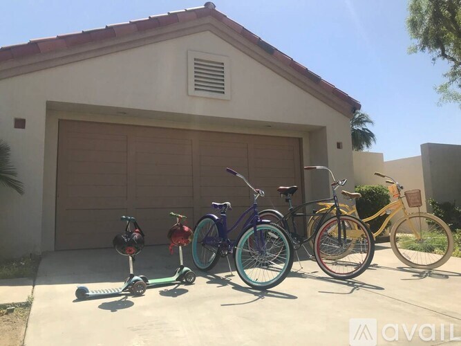 A row of bicycles and scooters are parked in front of a garage.