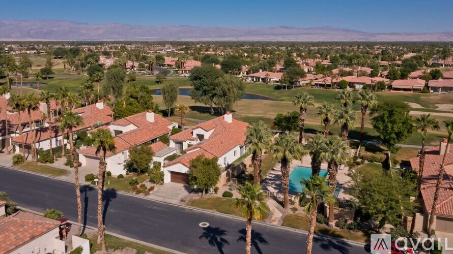 A bird's eye view of a residential area with houses, palm trees, and a pool.