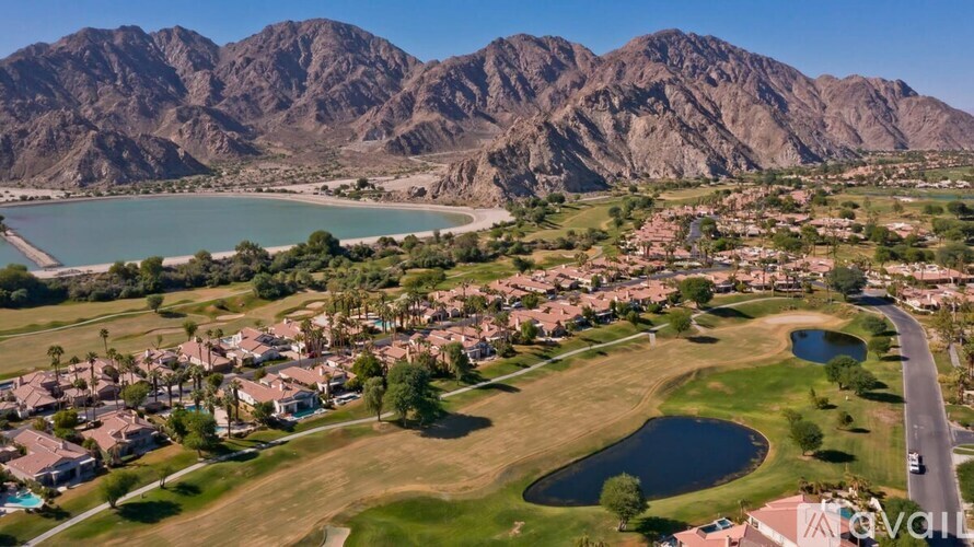 A bird's eye view of a residential area with houses, a lake, and mountains in the background.