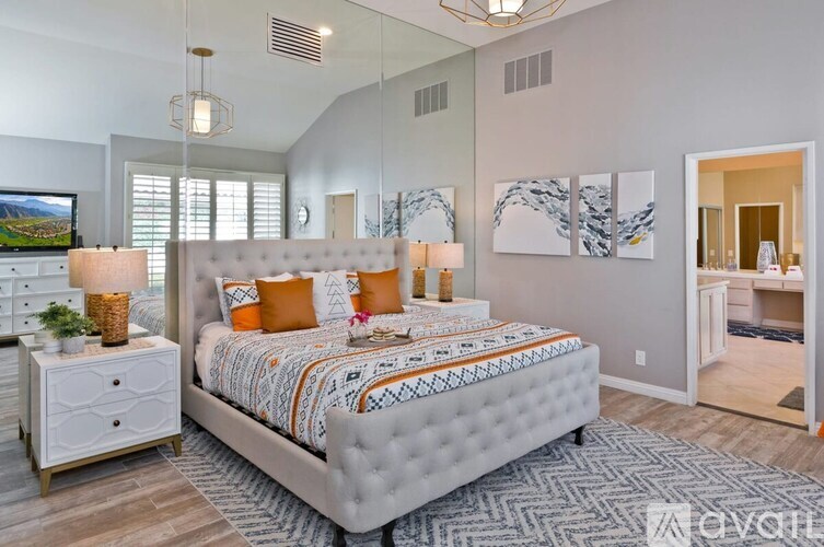 A bedroom with a large bed, a nightstand with a plant, and a TV on the wall.