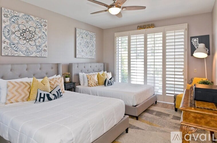 A bedroom with two beds, a ceiling fan, and a rug.