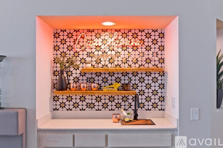 A kitchen with a wallpapered wall and a shelf with bottles and a vase.