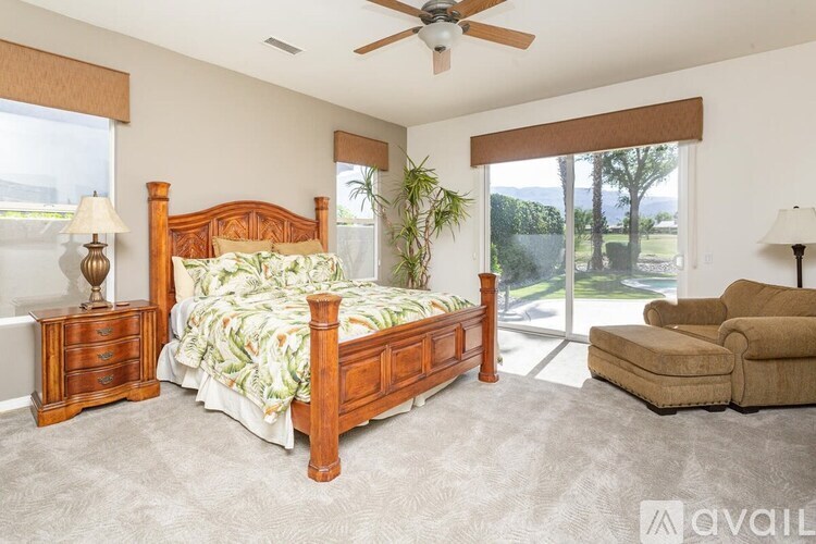 A bedroom with a large bed, a chair, and a ceiling fan.