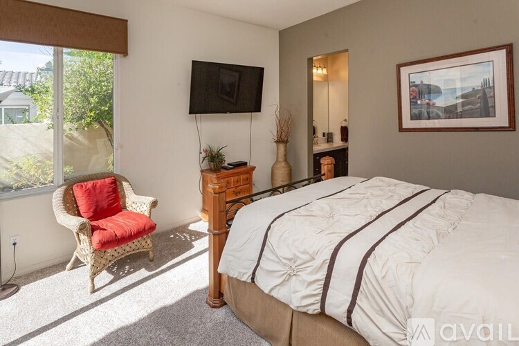 A bedroom with a large bed, a chair, and a television.