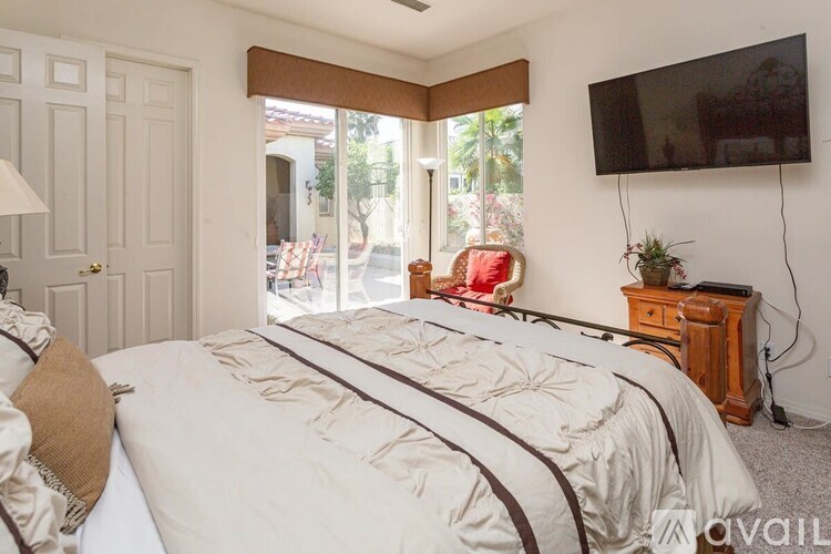 A bedroom with a large bed and a flat screen TV mounted on the wall.