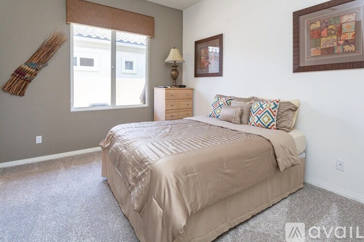 A bedroom with a bed, nightstand, lamp, and two pictures on the wall.