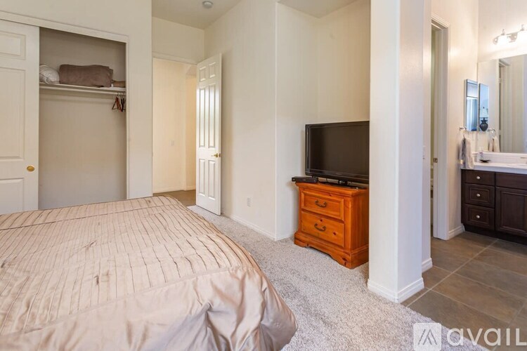 A bedroom with a large bed and a TV on a dresser.