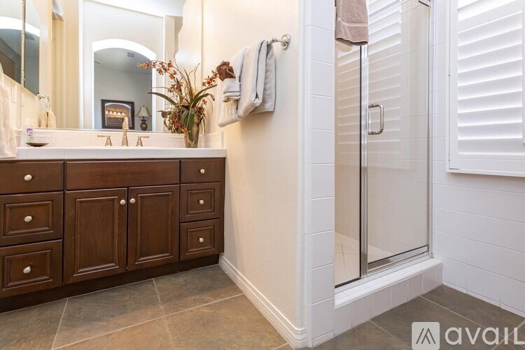 A bathroom with a white tiled shower and a wooden vanity.