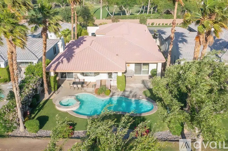 A house with a pool surrounded by palm trees.