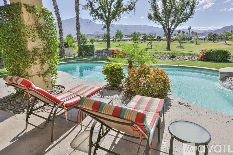 Two striped lawn chairs are on a patio next to a pool.