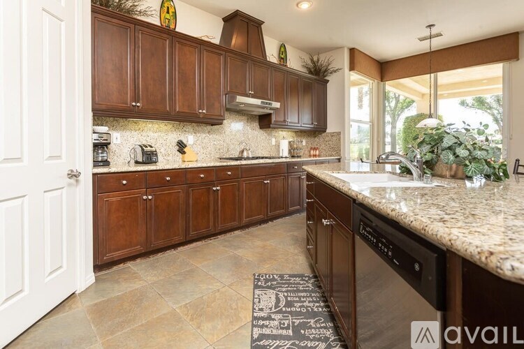 A kitchen with brown cabinets and a granite countertop.