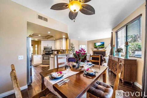 A dining room with a table set for two and a ceiling fan.
