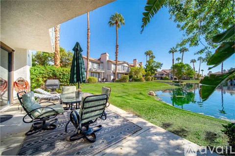 A patio with a table and chairs overlooking a pool.