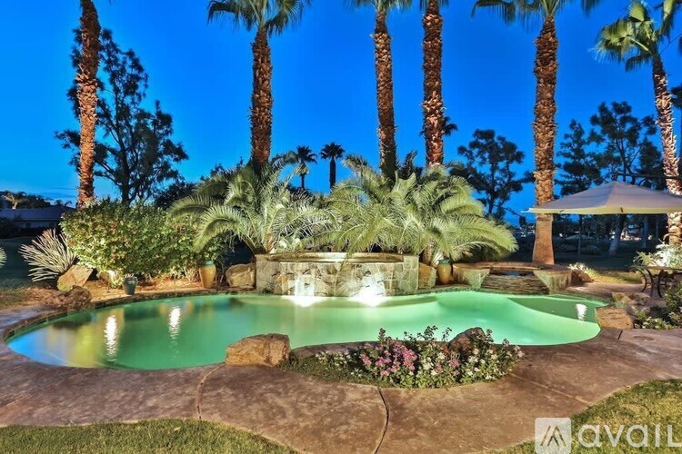A pool surrounded by palm trees at night.