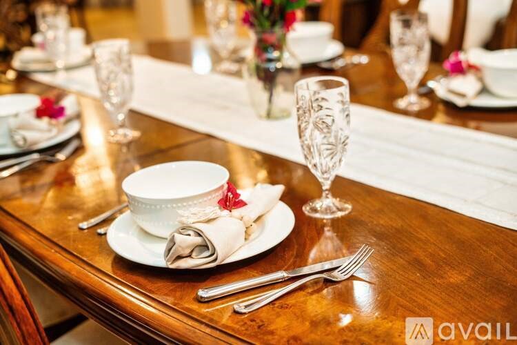 A table set for a meal with a white plate, a napkin, a fork, a knife, and a glass.