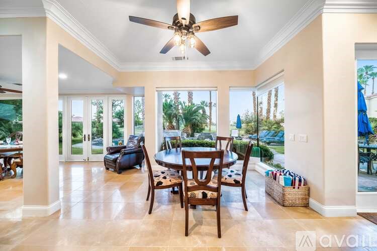 A sunny day at the beach with a house and chairs in the foreground.