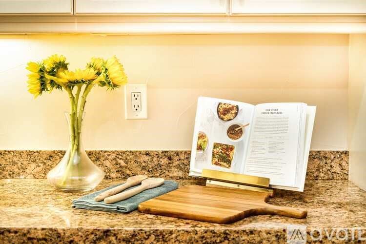 A kitchen counter with a vase of flowers, a cutting board, and an open cookbook.