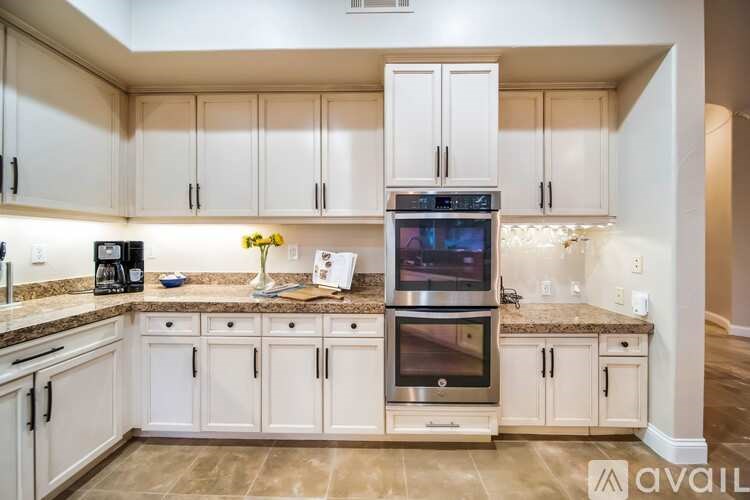 A kitchen with white cabinets and a stainless steel oven.