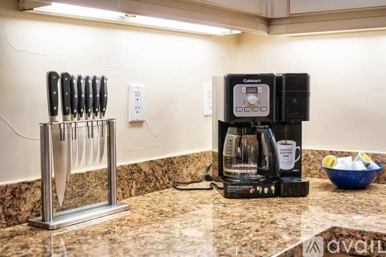 A coffee maker is on a counter next to a set of knives.