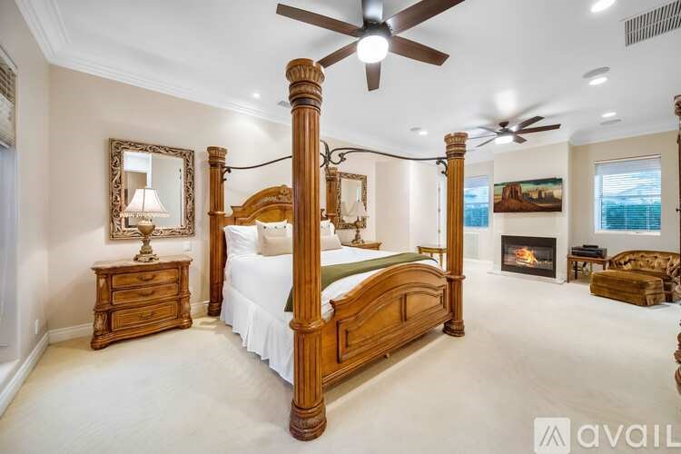 A bedroom with a large bed, a fireplace, and a ceiling fan.