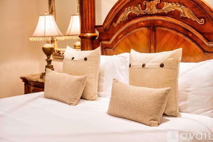 A bed with white pillows and a wooden headboard with a lamp on the side table.