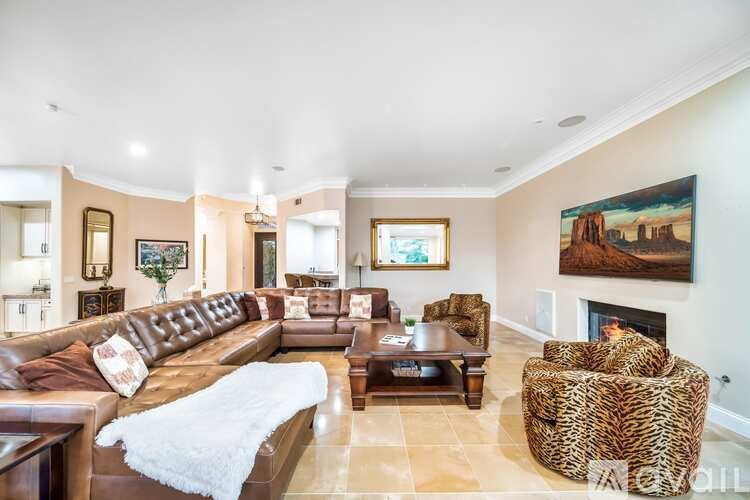 A living room with a brown leather couch and a fireplace.
