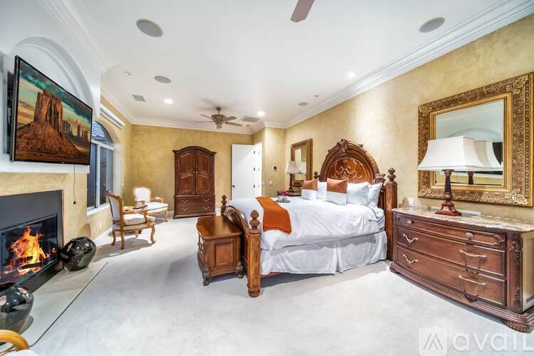 A bedroom with a fireplace and a painting of a desert scene on the wall.