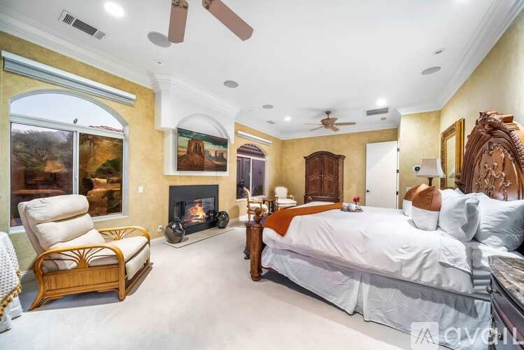 A bedroom with a large bed, a fireplace, and a painting on the wall.