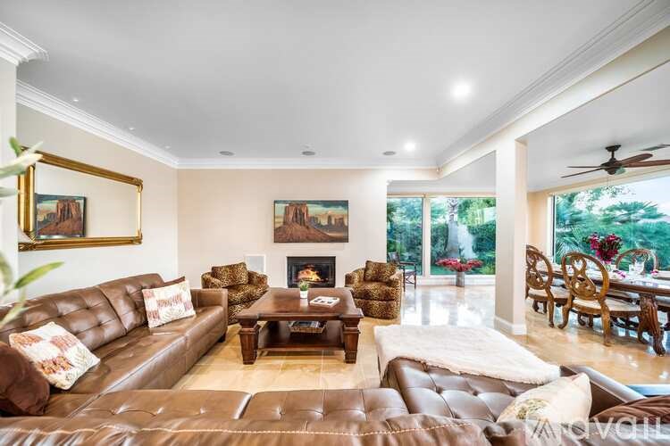 A living room with a brown leather couch and a painting on the wall.