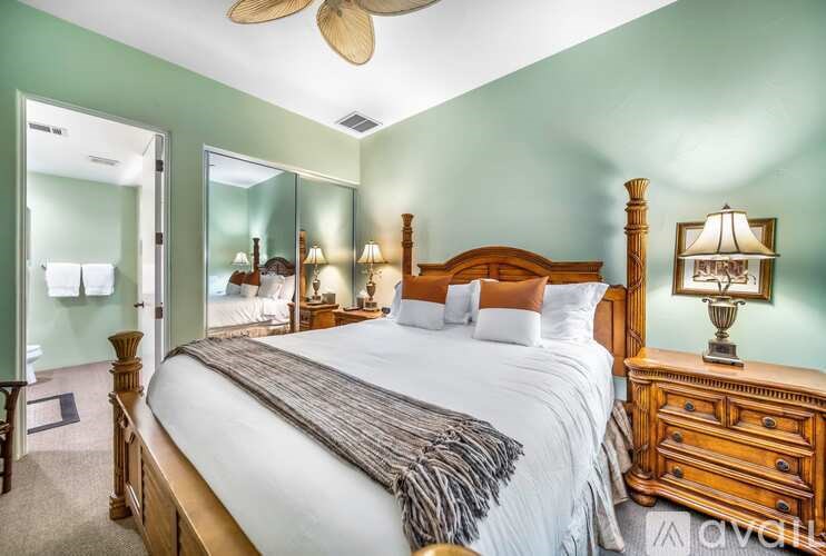 A bedroom with a large bed, wooden furniture, and a ceiling fan.