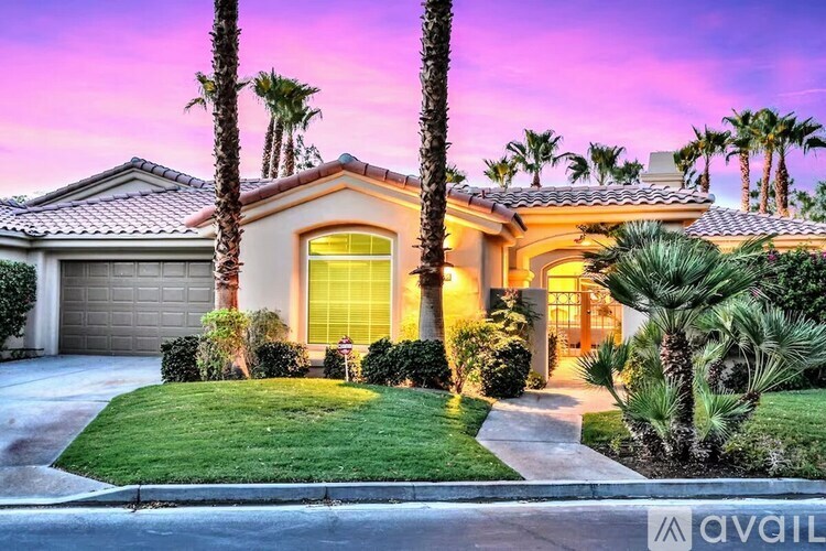 A house with a driveway and palm trees in front.
