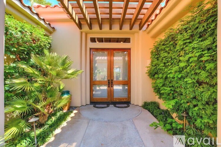 A wooden door is flanked by green plants on either side.
