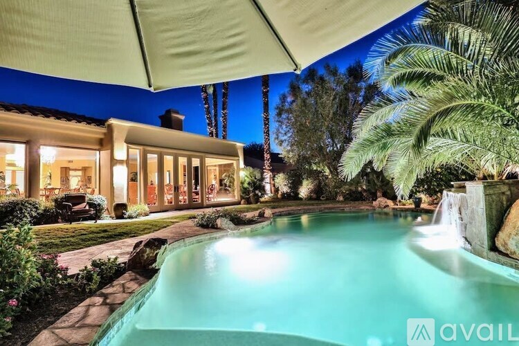 A house with a pool and palm trees in front.