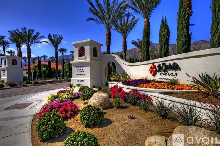 A sign for a resort and club is displayed in front of a landscaped area with palm trees.