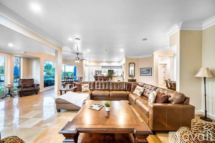 A spacious living room with a large brown leather couch and a wooden coffee table.